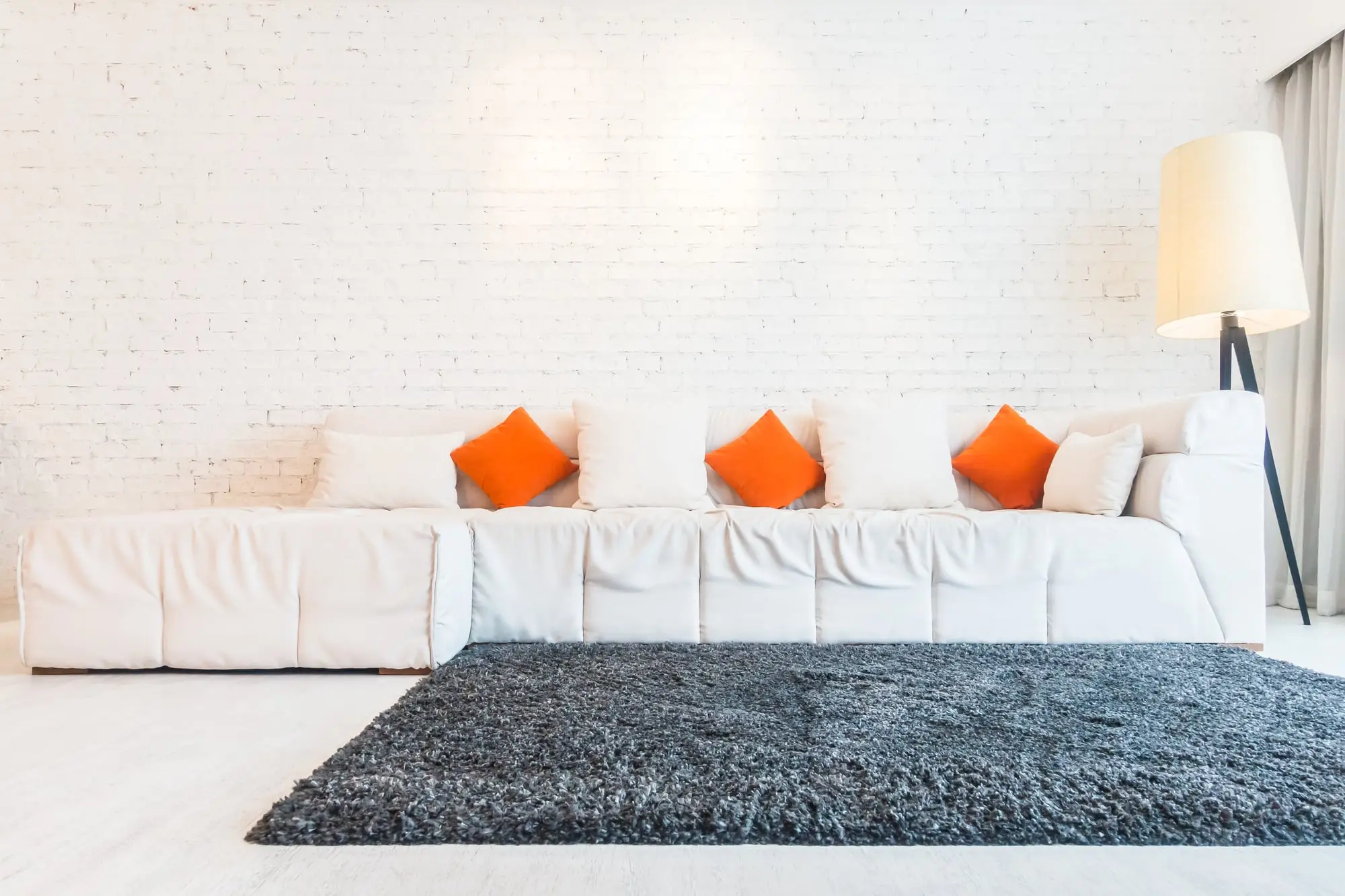 Biała sofa i ciemny dywan w jasnym salonie